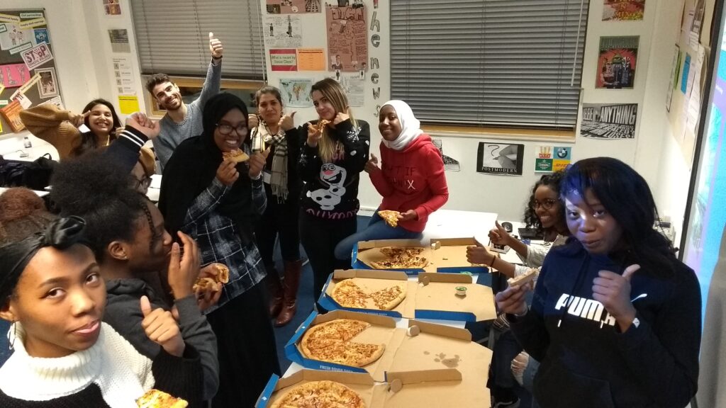 A classroom of young people eat pizza