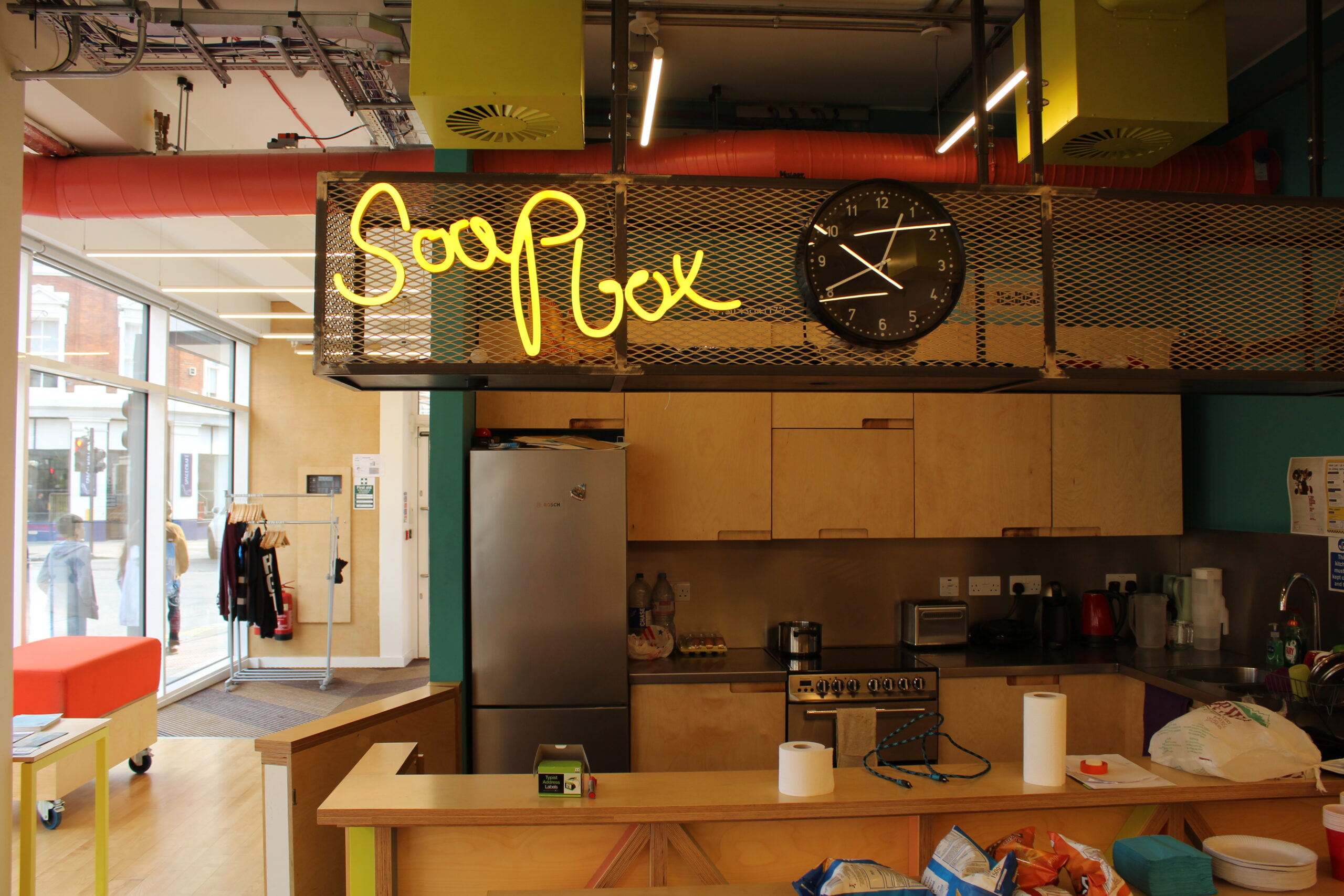 A neon sign above a kitchen reads 'soapbox'