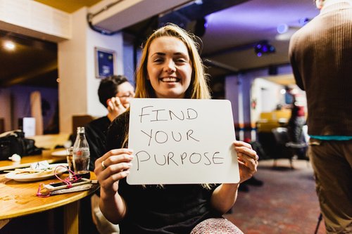 A person holds a sign saying Find Your Purpose
