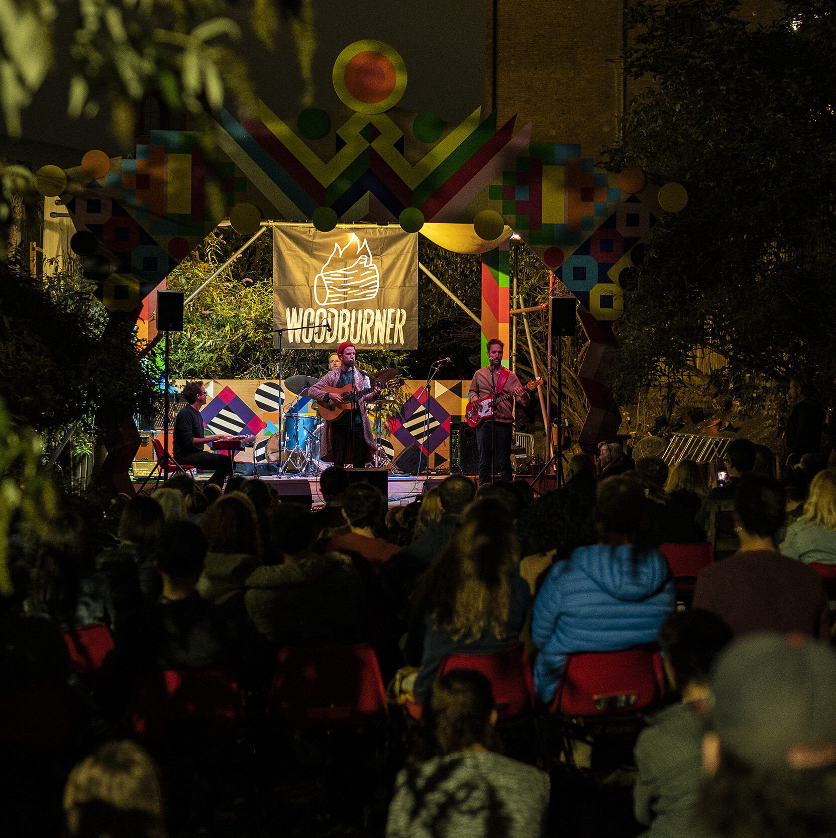 an image of an artist performing to an attentive crowd in a woodland area